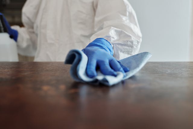 a hand with blue gloves cleaning a surface